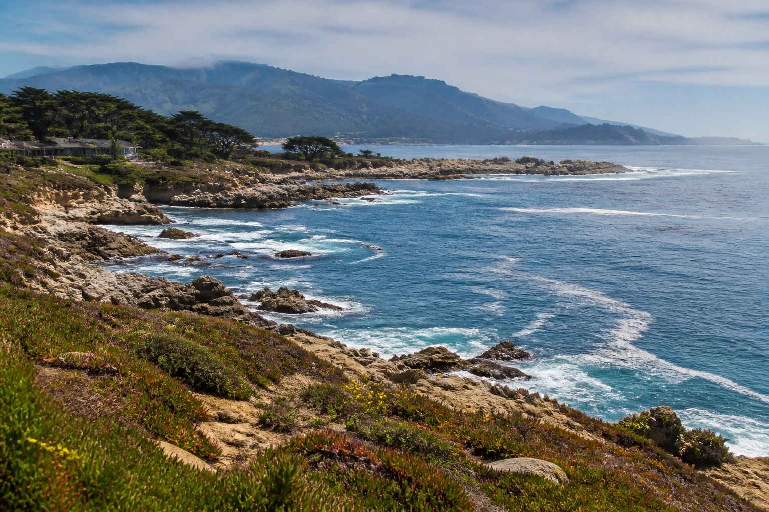 Representative coastal destination view: Monterey and Carmel-by-the-Sea, United States; coastline and regional vegetation, not an exact landmark photograph.
