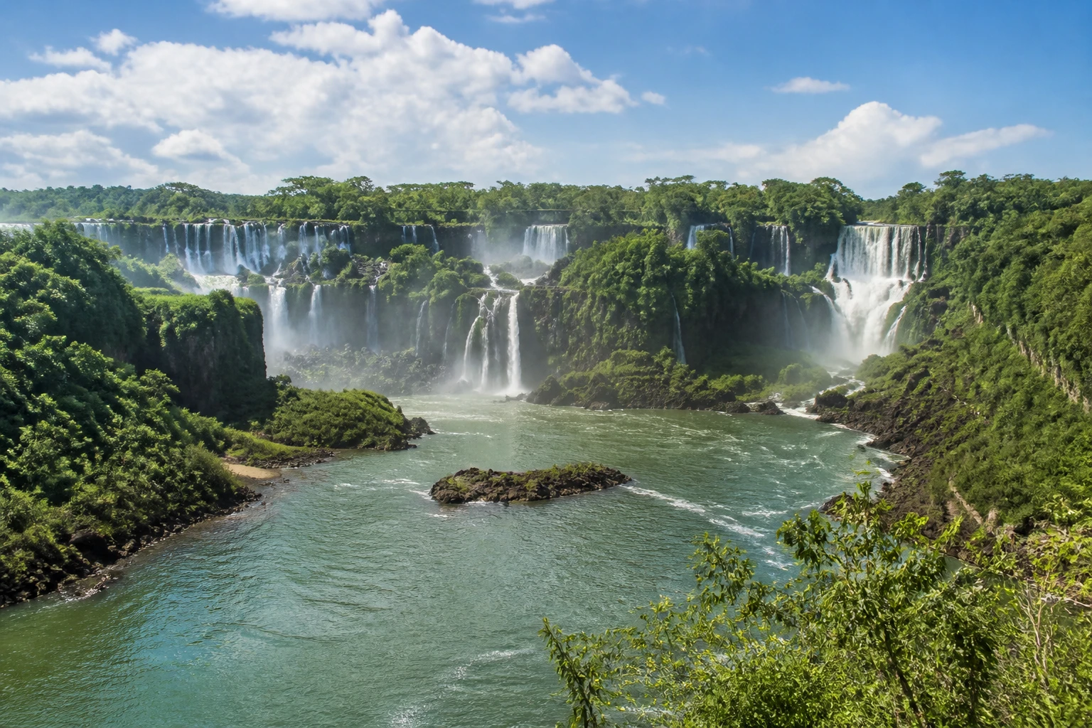 Representative nature destination view: Iguazu Falls, Argentina / Brazil; inland water, regional terrain, and vegetation, not an exact landmark photograph.