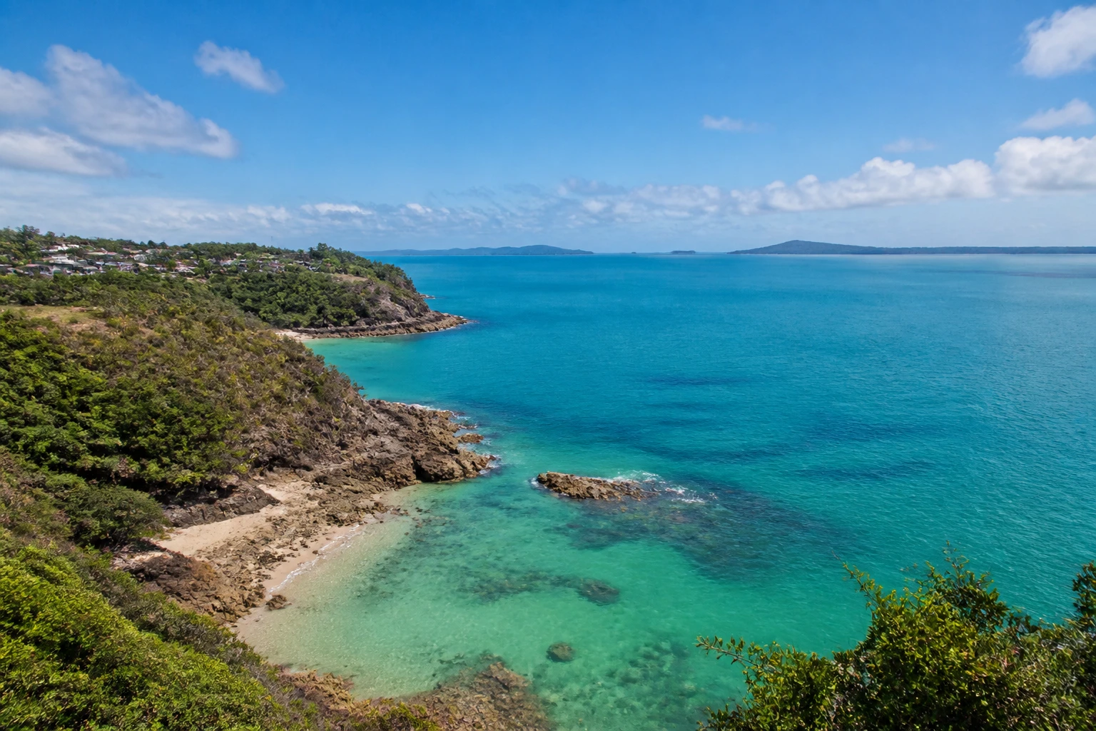 Representative cruise port destination view: Thursday Island, Australia; coastline and regional vegetation, not an exact landmark photograph.