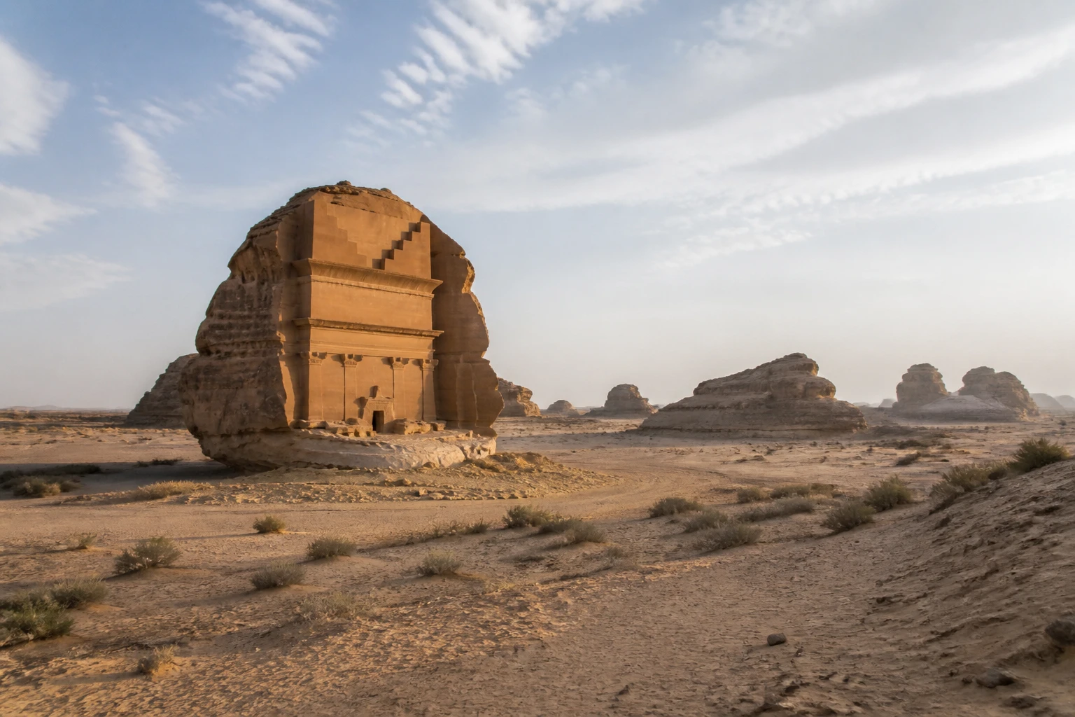 Representative desert destination view: AlUla, Saudi Arabia; desert terrain and sparse vegetation, not an exact landmark photograph.