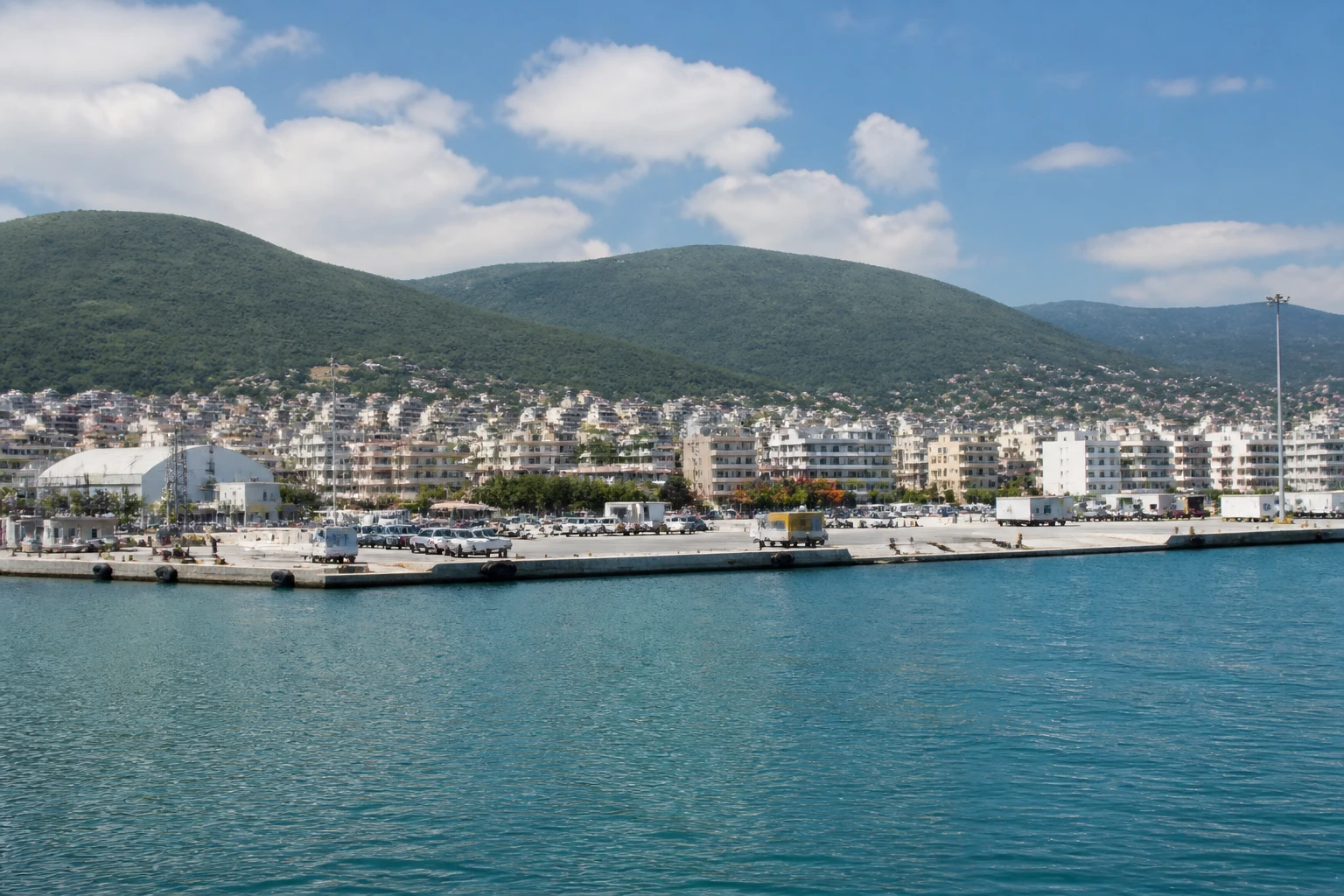 Representative cruise port destination view: Igoumenitsa, Greece; passenger waterfront and harbor water, not an exact landmark photograph.