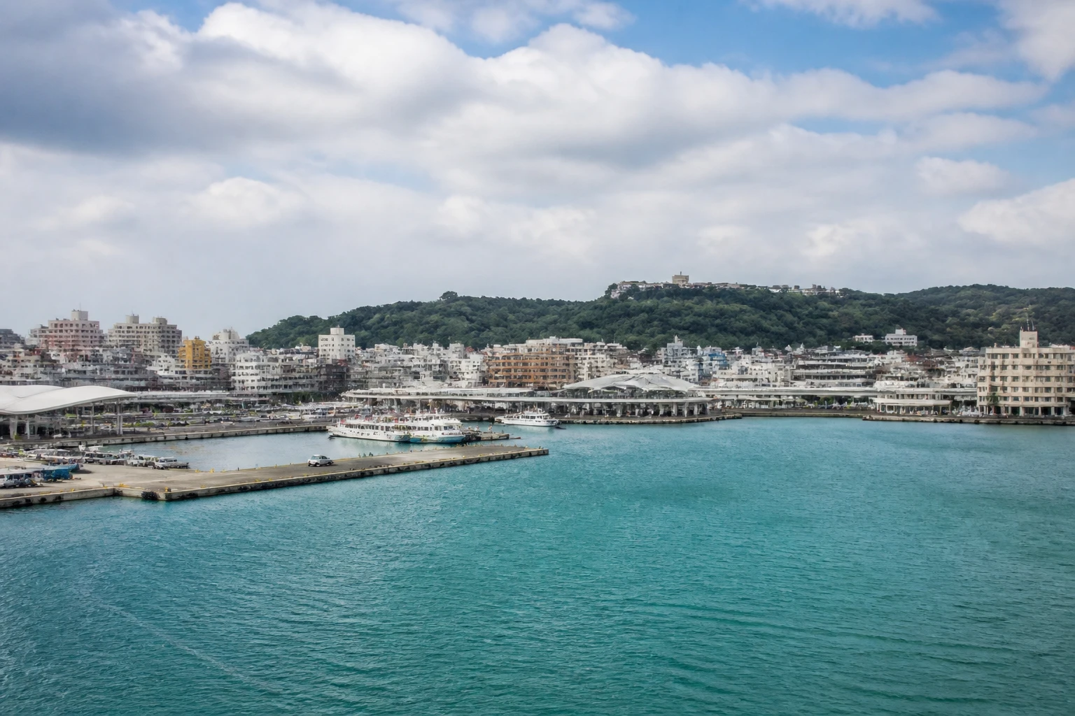 Representative cruise port destination view: Naha, Japan; passenger waterfront and harbor water, not an exact landmark photograph.