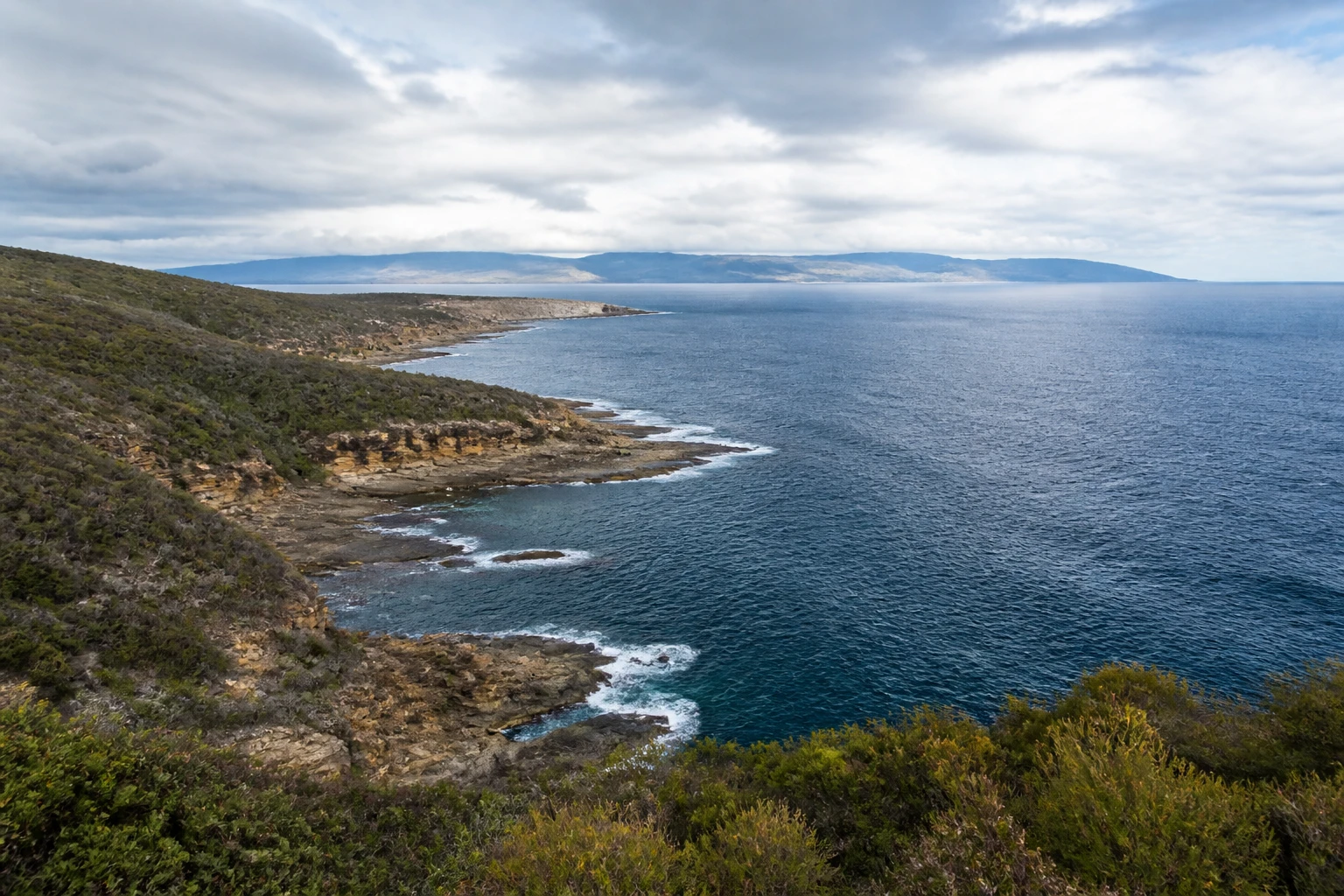 Representative island destination view: Tasmania and Hobart, Australia; coastline and regional vegetation, not an exact landmark photograph.