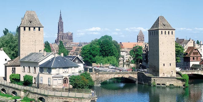Medieval stone towers, a canal bridge and Strasbourg Cathedral rising above the historic city in France.