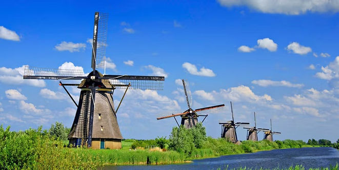 Traditional windmills beside calm waterways and green fields at Kinderdijk Windmills.