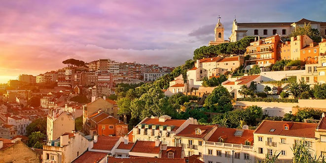 Warm evening light across Lisbon's tiled rooftops, church towers and hillside neighborhoods in Portugal.
