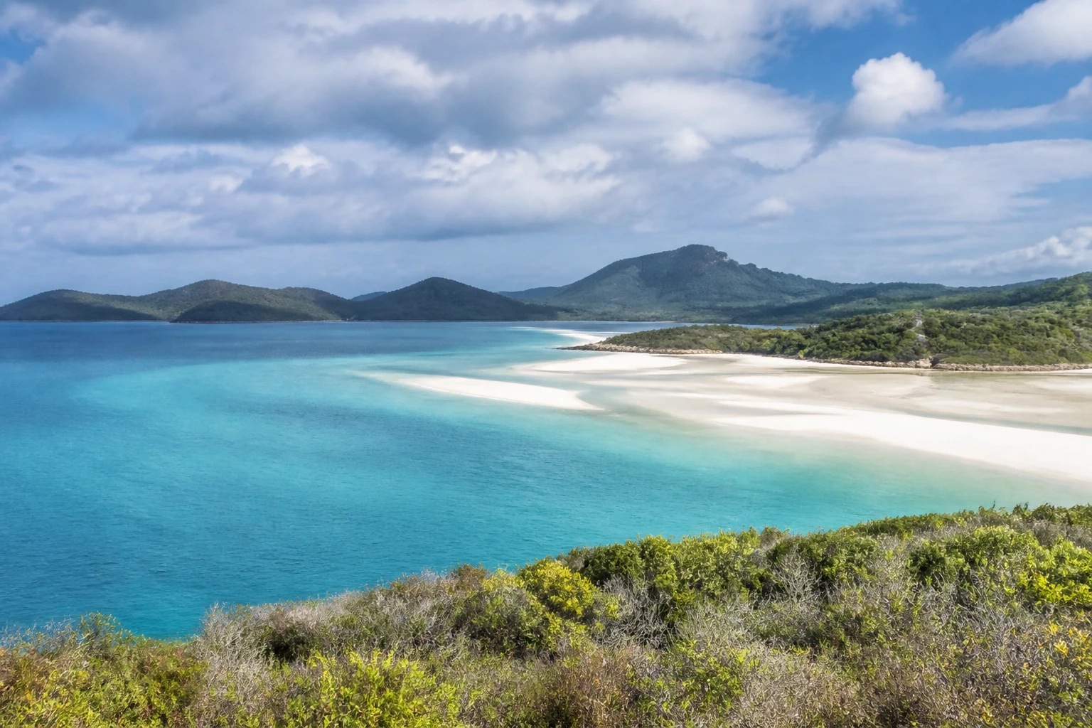 Representative island destination view: Whitsunday Islands, Australia; coastline and regional vegetation, not an exact landmark photograph.