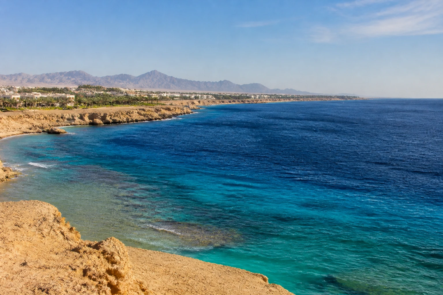 Representative coastal destination view: Sharm el-Sheikh, Egypt; coastline and regional vegetation, not an exact landmark photograph.