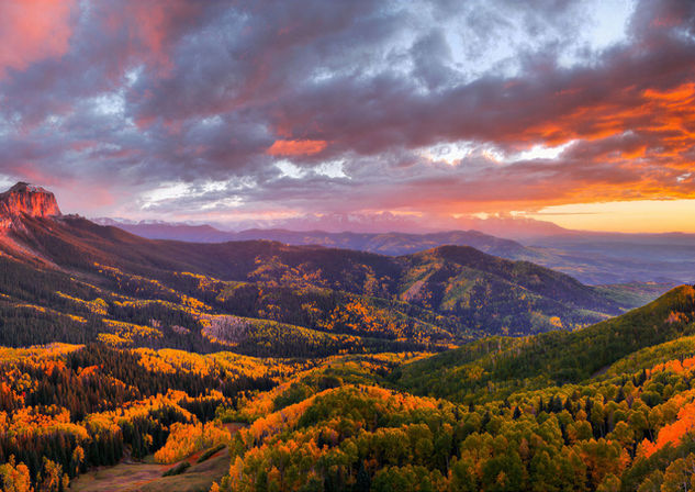 Colorado mountain landscape with golden autumn trees and dramatic sunset sky.
