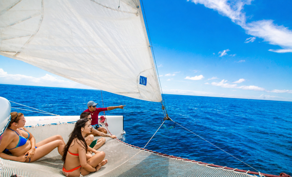 Travelers sailing aboard a catamaran charter on the blue Caribbean waters surrounding Roatán, Honduras