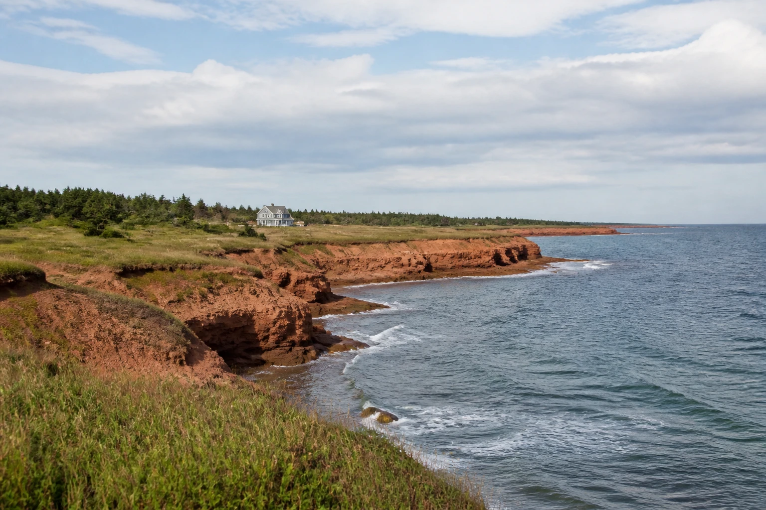 Representative island destination view: Prince Edward Island, Canada; coastline and regional vegetation, not an exact landmark photograph.
