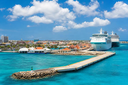 Cruise ships at the unbranded Oranjestad cruise port beside turquoise water in Aruba