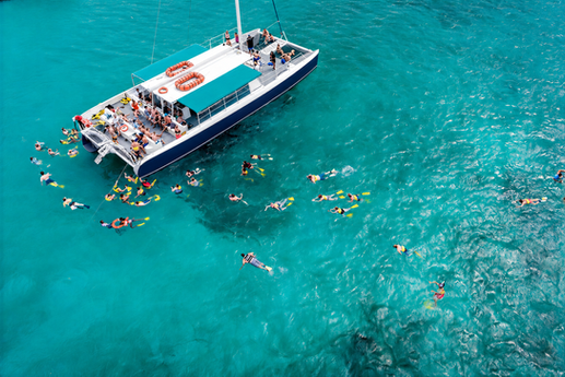 Catamaran surrounded by travelers snorkeling in clear Caribbean water during a Jamaica excursion