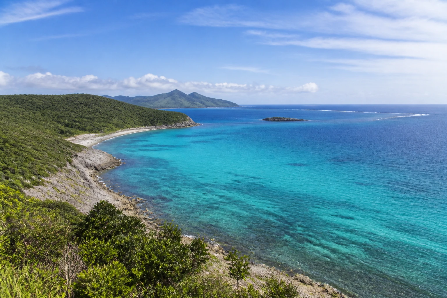 Representative island destination view: New Caledonia; coastline and regional vegetation, not an exact landmark photograph.