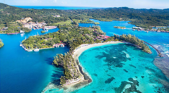Aerial view of Roatán, Honduras, featuring turquoise bays, coral reefs and lush tropical hills
