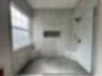remodeled master shower with new tiles, custom cut niche, two benches in the corners for sitting during showering, a handheld showerhead