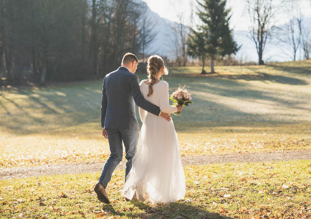 Brautpaar läuft Hand in Hand durch die Abendsonne im Allgäu
