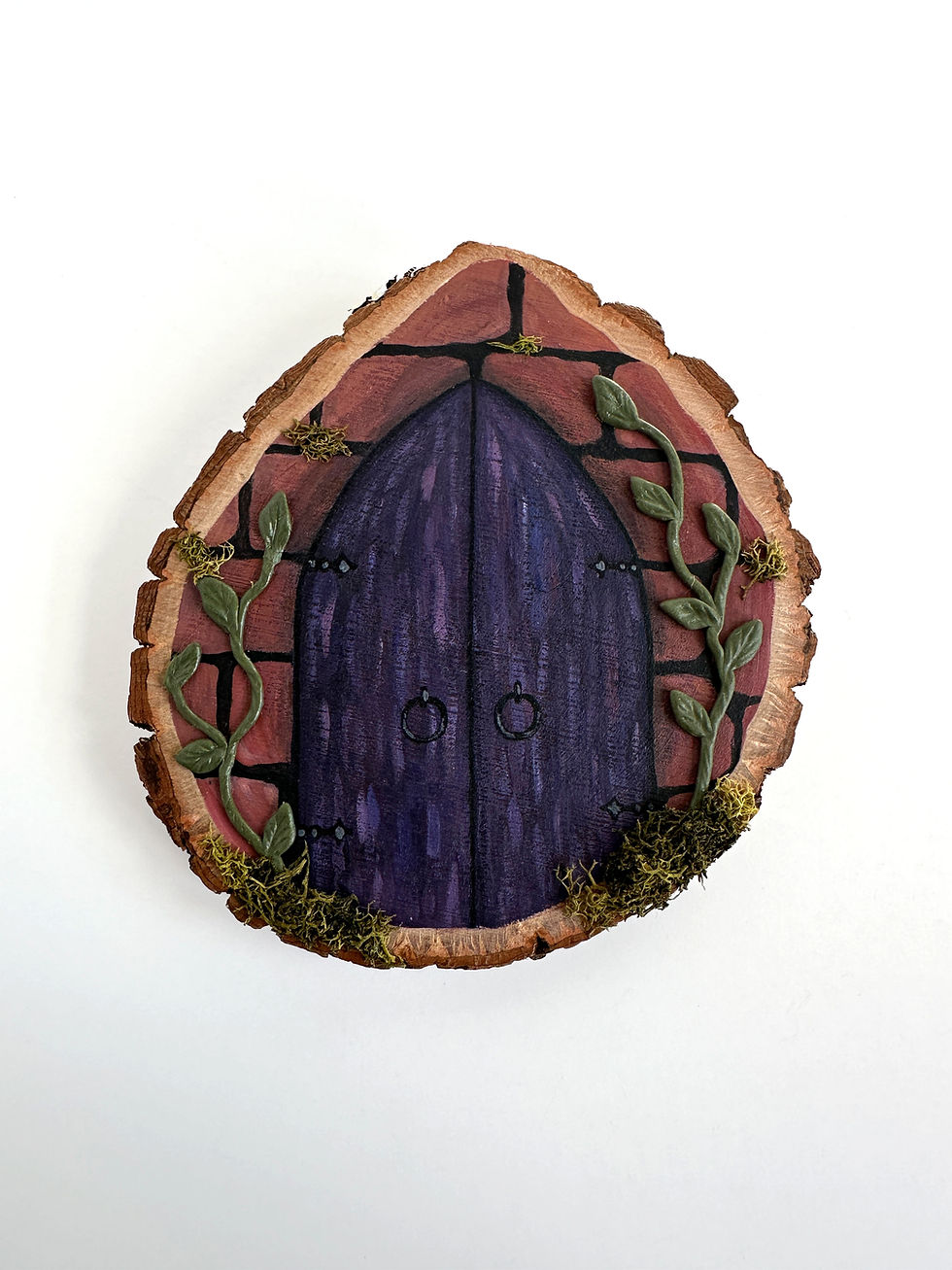 A wood slice painted with purple gothic doors and red brick with green vines