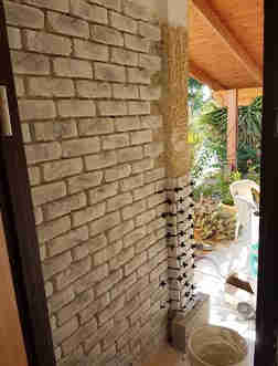 התקנת בריק לבן עם נגיעות שחור-אפרפר על קיר עם דבק