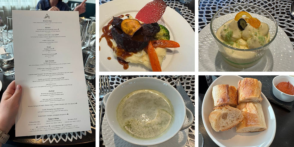 Hand holding a restaurant menu; plates with mashed potato and beef, dessert with fruit garnish, green soup, and bread with red dip on display.