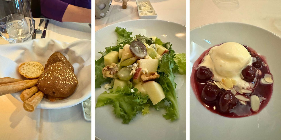 Three plated courses on a restaurant table: bread basket, apple grape salad, and cherry dessert with ice cream and almonds