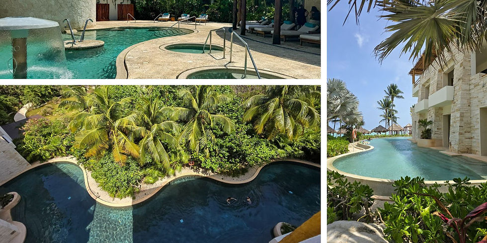 Tropical resort pool with waterfall, surrounded by lush palms and loungers. Bright blue skies and ocean in the background. Relaxing vibe.