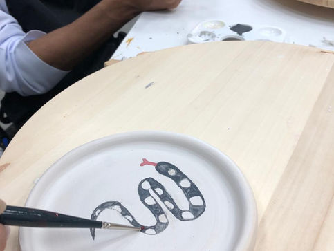 ceramic plate with a painting of a black snake being produced