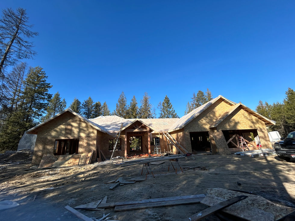 The front of a house with all the sheathing and framing done with two garage openings three windows and a door in Sandpoint Idaho
