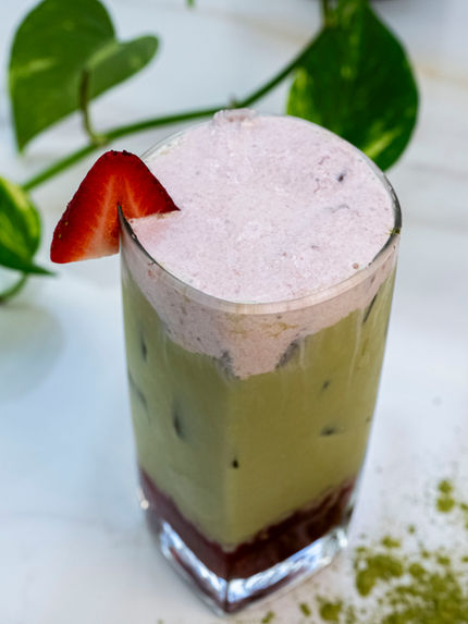 Iced matcha latte with strawberry topping and a strawberry slice garnish
