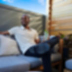 Dating app photographer client in a cream polo relaxing with a cocktail on a sunny rooftop lounge