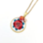 Collier avec un pendentif représentant une rose rouge en broderie sur fond blanc, en mode zoom pour apprécier les détails.