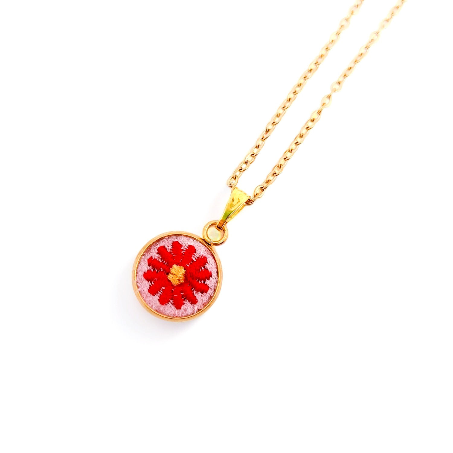 Photo du Collier Marguerite rouge sur fond rose en broderie avec une monture dorée