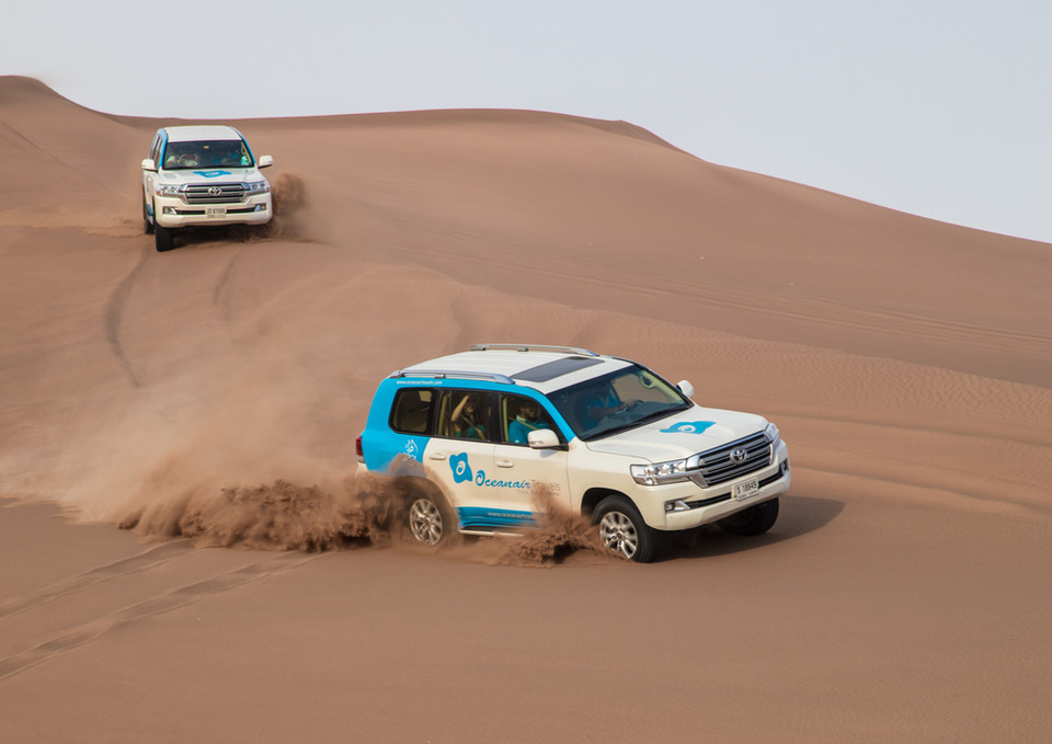 Two white SUVs drifting in desert sands, shot for dynamic off-road car photography in UAE