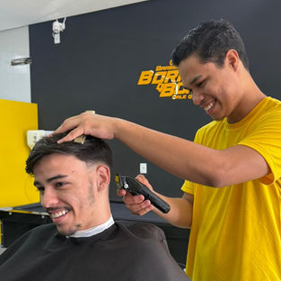 Barbeiro cortando cabelo de cliente sorrindo