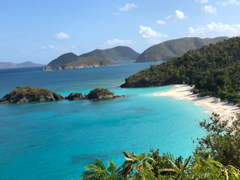 Turquoise water and white sand beach at Trunk Bay on St. John, framed by lush green hills and islands.