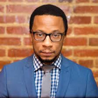 Joseph Green headshot. Black man wearing glasses, blue sport coat with blue and white checked shirt and grey tie