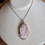 Thumbnail: Pink spotted crystal in a silver necklace setting