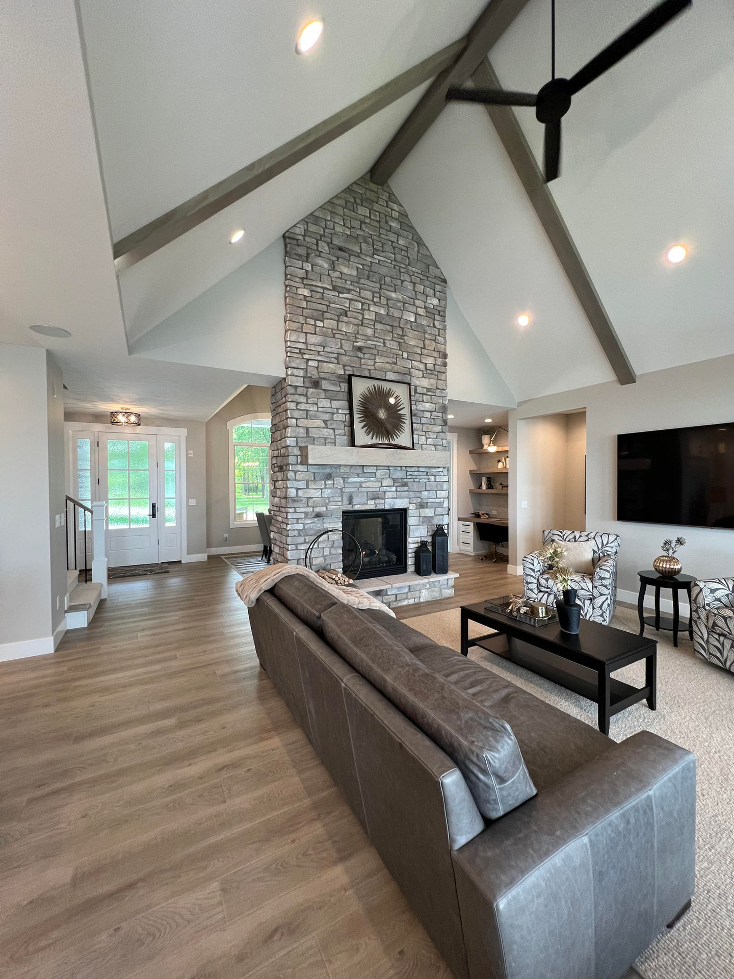 Vaulted living room with wood beams and a stone fireplace