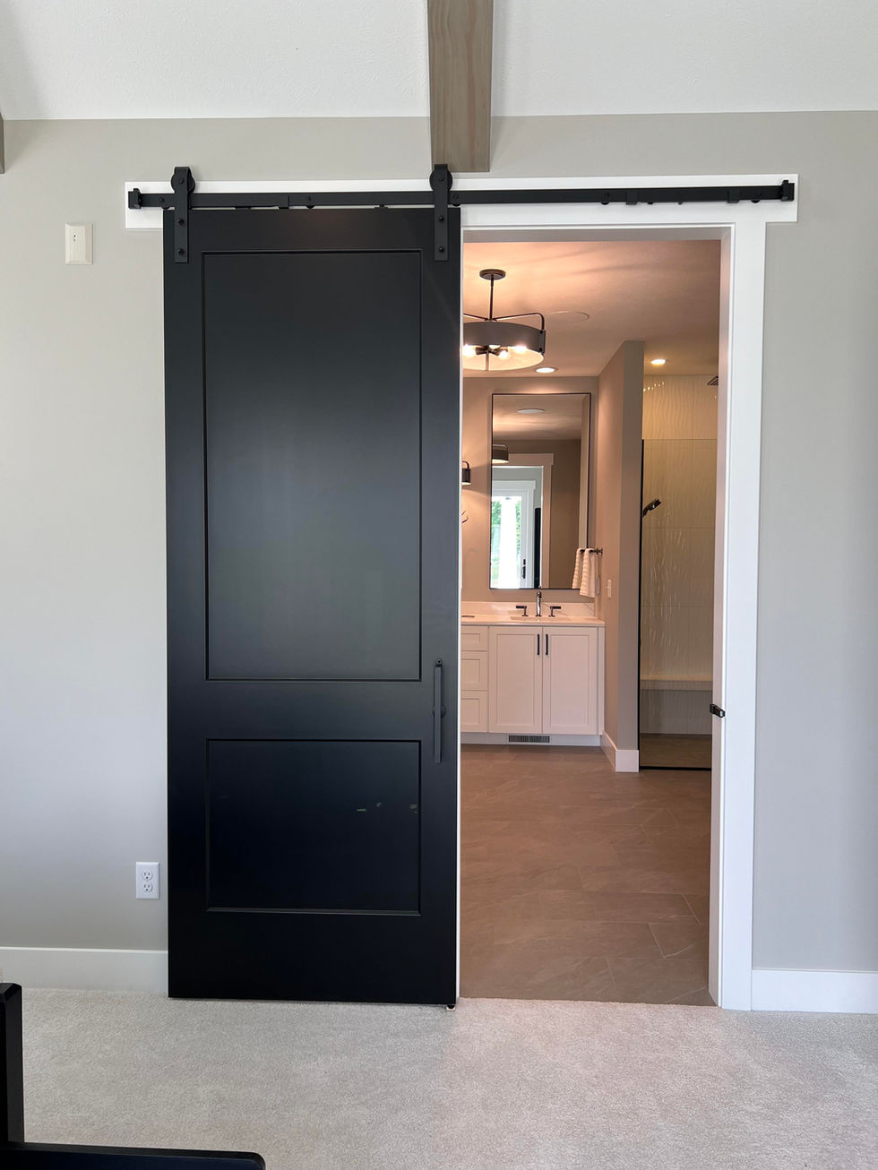 Black sliding barn door opens into owners bathroom