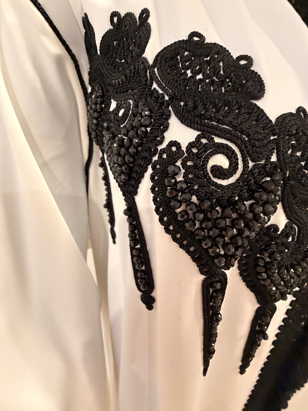 White hooded jellaba with black floral embroidery on chest and cuffs.White hooded jellaba