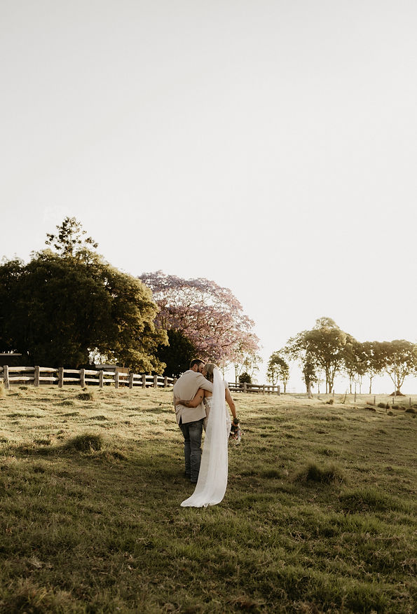 Sunset over farm with bride and groom holding each other.
