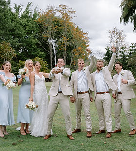 Bridal party popping champagne for photo