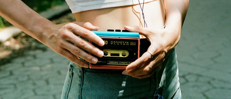 An image of a classic walkman clipped on a women's hip