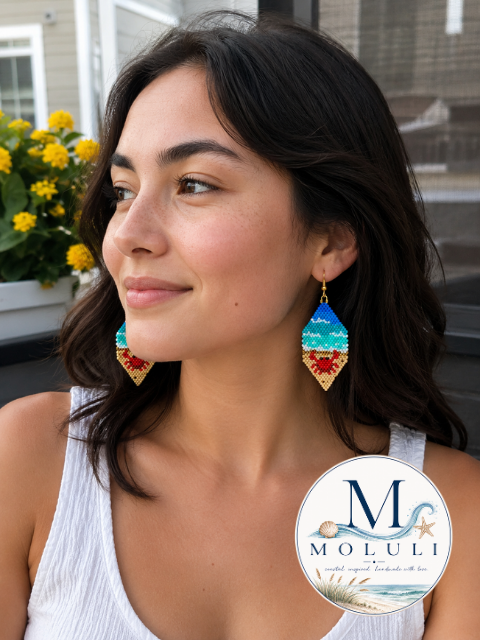 Model wearing Crabby Cabana beaded earrings with red crabs, turquoise waves, and 18k gold-plated fishhooks.