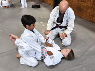 Kids Brazilian Jiu-Jitsu class with coach teaching two children at Martial Arts & More of Wilmington