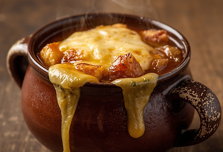 Französische Zwiebelsuppe in einer rustikalen Keramiktasse, mit geschmolzenem goldbraunem
