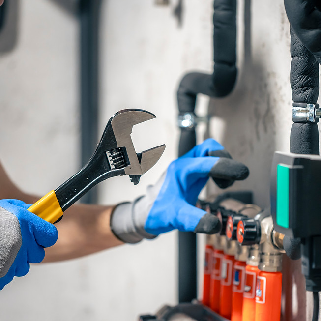 man-installs-heating-system-house-checks-pipes-with-wrench.jpg