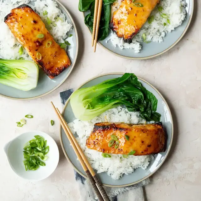A picture of plates with rice, bok choy, and glazed salmon fillets