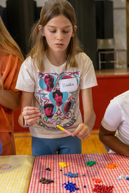 A young girl making a beaded bracelet