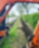 Small orange digger digging a drainage ditch at roadside
